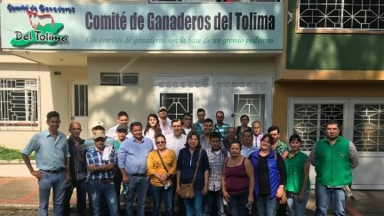 Grupo de ganaderos frente a la sede del Comité de Ganaderos del Tolima, con un letrero que destaca el compromiso con el gremio